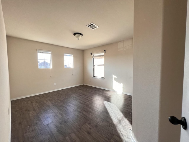 spare room with a healthy amount of sunlight and dark hardwood / wood-style flooring