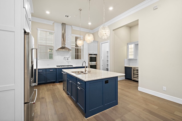 kitchen with sink, wall chimney exhaust hood, tasteful backsplash, white cabinetry, and stainless steel appliances