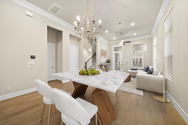 dining room with ceiling fan with notable chandelier, light hardwood / wood-style floors, and crown molding