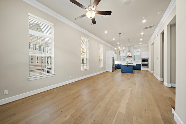 unfurnished living room with ceiling fan with notable chandelier, light hardwood / wood-style flooring, ornamental molding, and sink