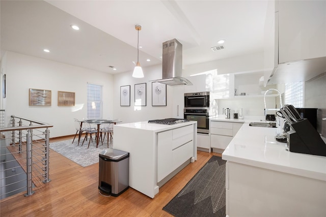 kitchen featuring white cabinets, sink, light hardwood / wood-style floors, decorative light fixtures, and island range hood