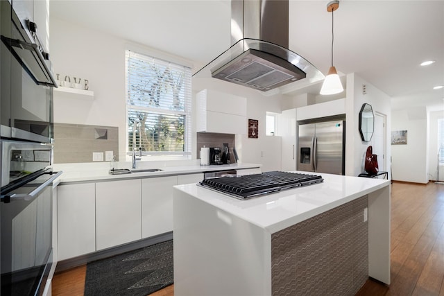 kitchen with island exhaust hood, white cabinets, and appliances with stainless steel finishes