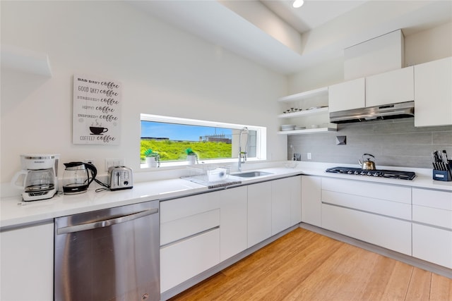 kitchen with gas stovetop, stainless steel dishwasher, extractor fan, white cabinets, and light wood-type flooring