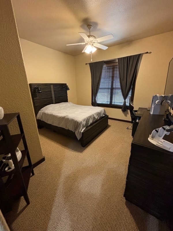 bedroom with a textured ceiling, carpet floors, and ceiling fan