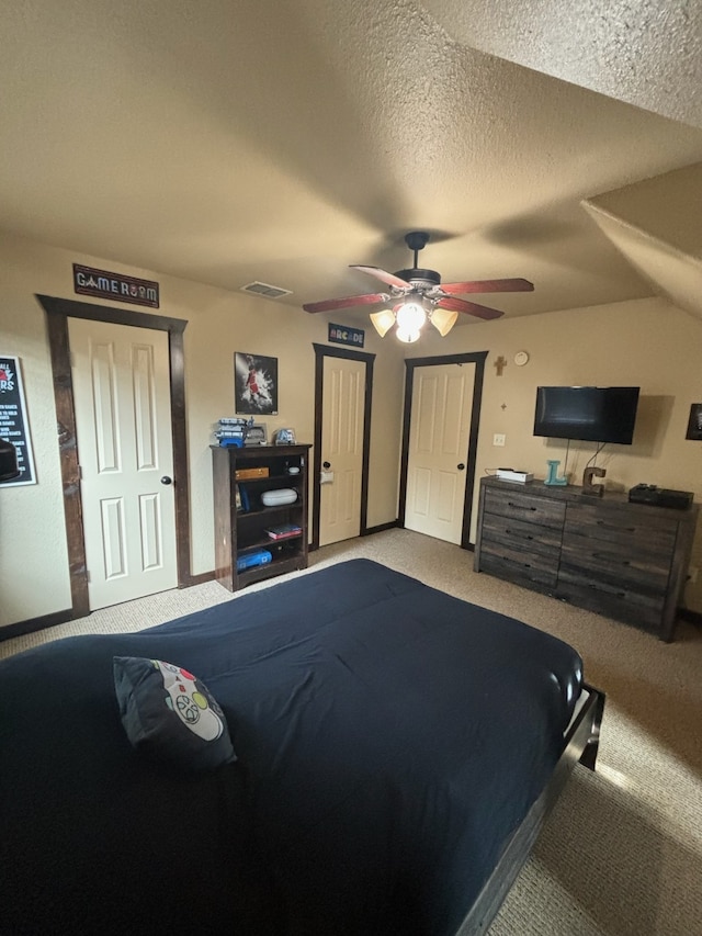 bedroom with ceiling fan, carpet floors, and a textured ceiling