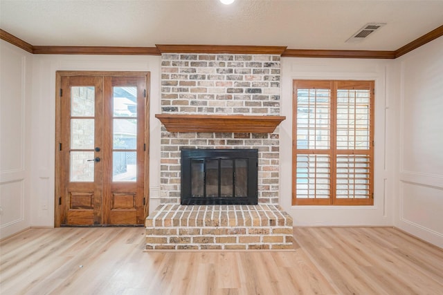 unfurnished living room with a fireplace, french doors, light hardwood / wood-style floors, and ornamental molding