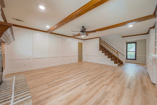 unfurnished living room featuring a brick fireplace, a textured ceiling, ceiling fan, light hardwood / wood-style flooring, and beamed ceiling