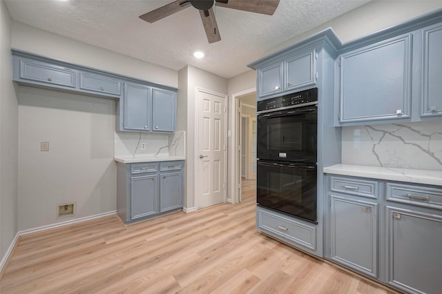 kitchen with double oven, decorative backsplash, light hardwood / wood-style flooring, and ceiling fan