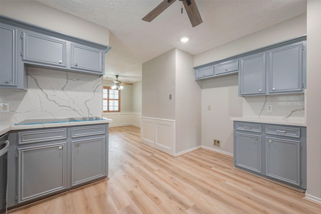 kitchen with gray cabinetry, tasteful backsplash, stainless steel dishwasher, black electric stovetop, and light wood-type flooring