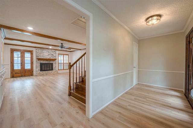 interior space featuring crown molding, light wood-type flooring, a textured ceiling, and french doors