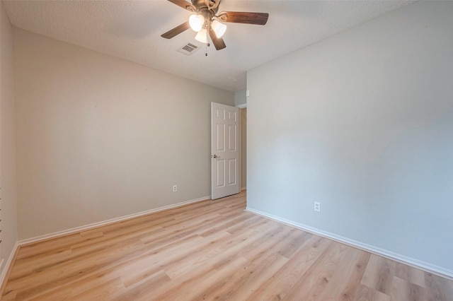 empty room featuring a textured ceiling, light wood-type flooring, and ceiling fan