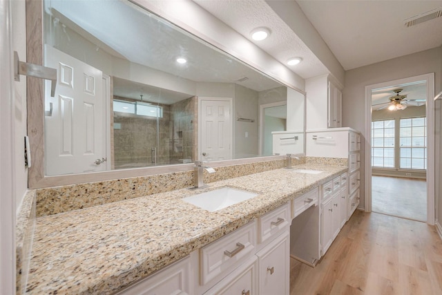 bathroom with hardwood / wood-style floors, vanity, ceiling fan, and a shower with shower door