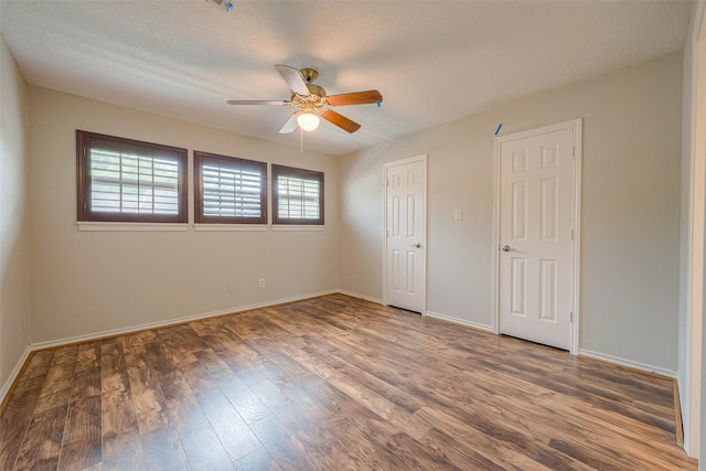 unfurnished bedroom featuring a textured ceiling, ceiling fan, and dark hardwood / wood-style floors