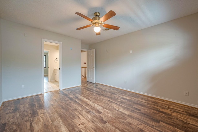 unfurnished bedroom featuring a textured ceiling, dark hardwood / wood-style flooring, ensuite bathroom, and ceiling fan