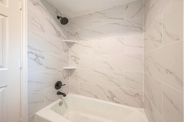 bathroom featuring a textured ceiling and tiled shower / bath combo