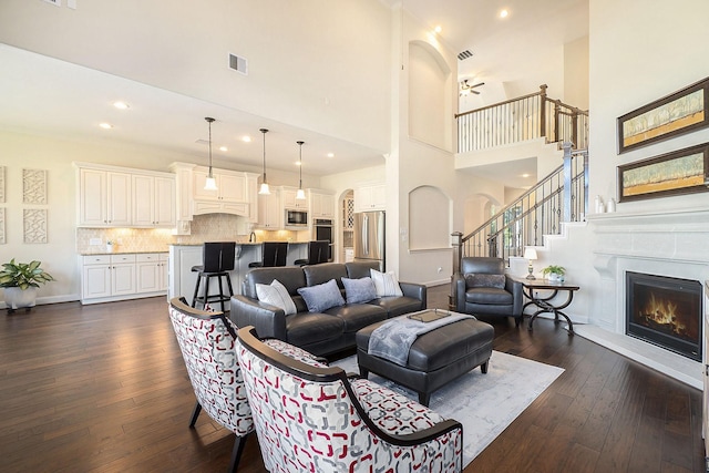 living room featuring ceiling fan, a high ceiling, and dark hardwood / wood-style floors