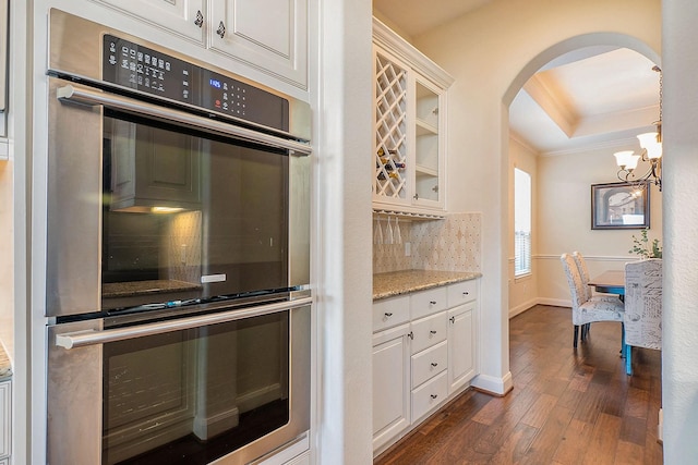 kitchen with a raised ceiling, white cabinetry, and stainless steel double oven