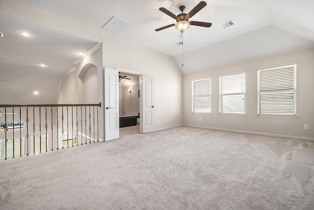 empty room with ceiling fan, light colored carpet, ornamental molding, and vaulted ceiling