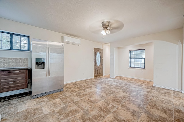 kitchen featuring a textured ceiling, dark brown cabinetry, ceiling fan, an AC wall unit, and stainless steel fridge with ice dispenser