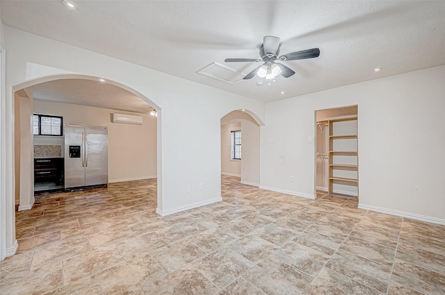 spare room with a wall mounted AC, ceiling fan, and a textured ceiling