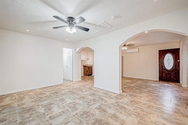 interior space with a wall unit AC, ceiling fan, and a textured ceiling