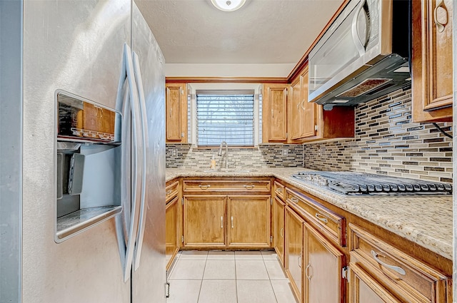 kitchen with light stone countertops, sink, decorative backsplash, light tile patterned flooring, and appliances with stainless steel finishes