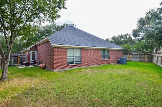 rear view of house with a yard, cooling unit, and a patio