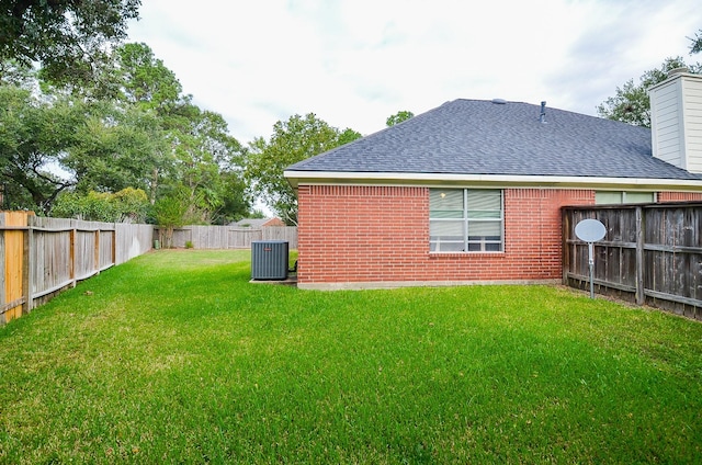 rear view of property featuring central air condition unit and a yard