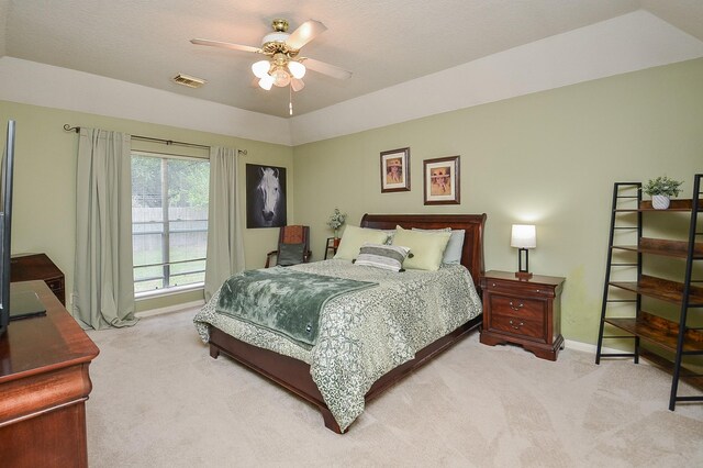 carpeted bedroom featuring ceiling fan and a raised ceiling