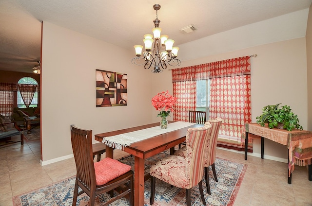 tiled dining area with ceiling fan with notable chandelier