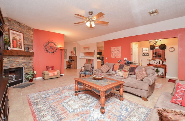 living room with ceiling fan, a fireplace, light tile patterned floors, and a textured ceiling