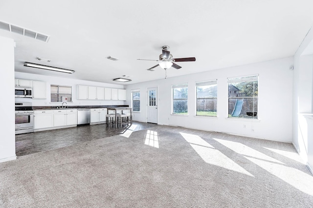 unfurnished living room with ceiling fan, carpet floors, and sink