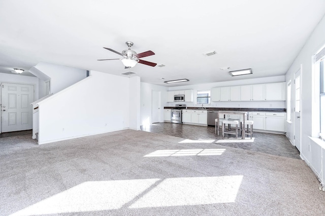 unfurnished living room with ceiling fan, sink, and dark colored carpet