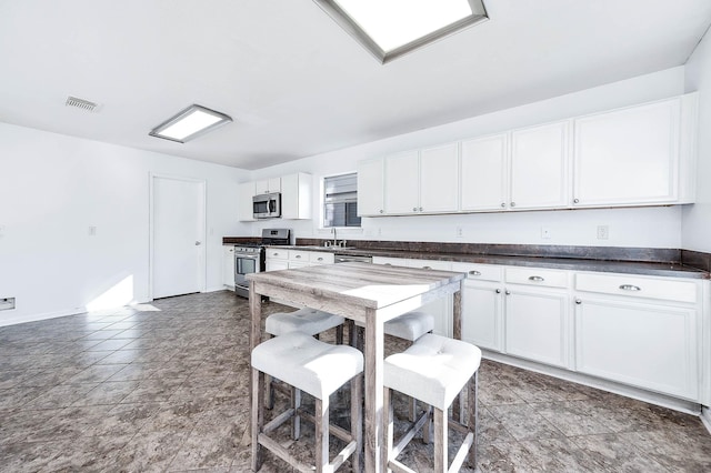 kitchen with a breakfast bar, white cabinets, stainless steel appliances, and sink