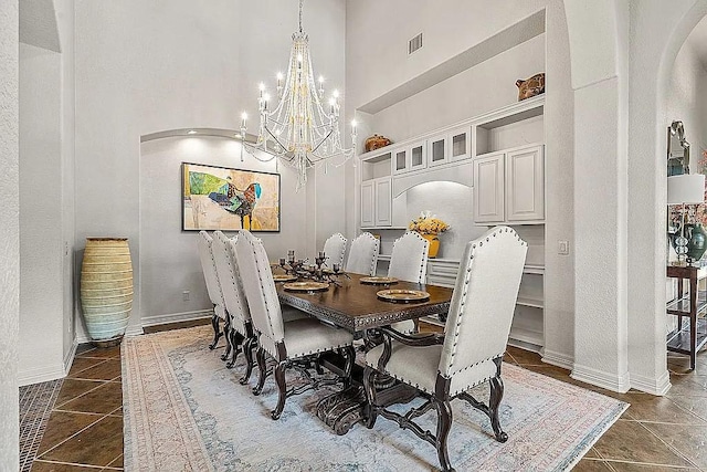 dining space featuring dark tile patterned floors, a towering ceiling, and a chandelier