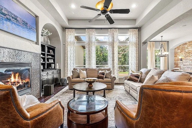 interior space featuring a tiled fireplace and ceiling fan with notable chandelier