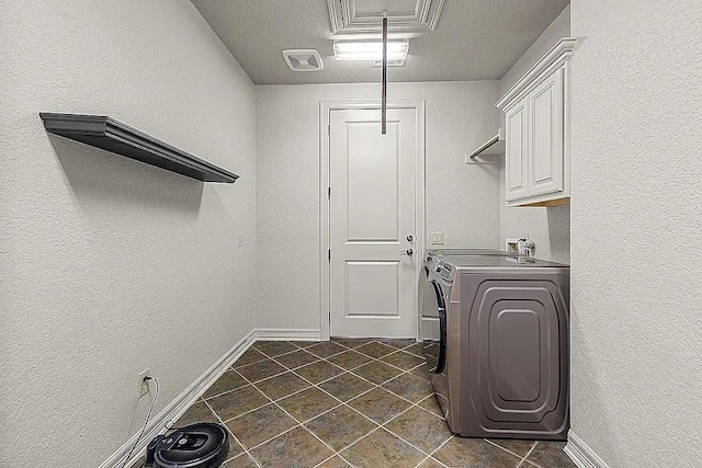 clothes washing area featuring cabinets, separate washer and dryer, and a textured ceiling