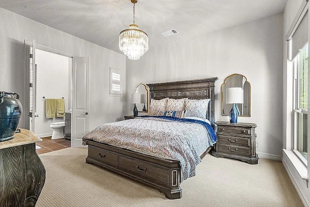 bedroom with carpet, ensuite bathroom, and a notable chandelier