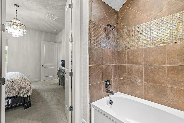 bathroom with a textured ceiling, tiled shower / bath, and a notable chandelier