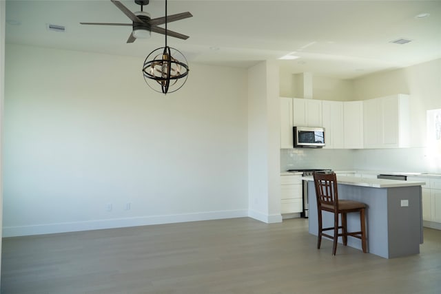 kitchen with a breakfast bar area, appliances with stainless steel finishes, a kitchen island, decorative backsplash, and white cabinets