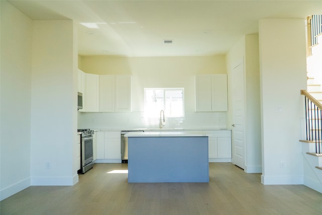 kitchen featuring tasteful backsplash, a kitchen island, white cabinets, and appliances with stainless steel finishes