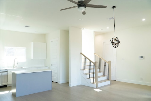 kitchen with pendant lighting, sink, dishwasher, white cabinets, and a kitchen island