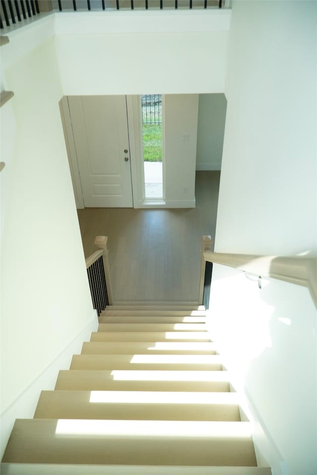 stairway with hardwood / wood-style floors and a high ceiling