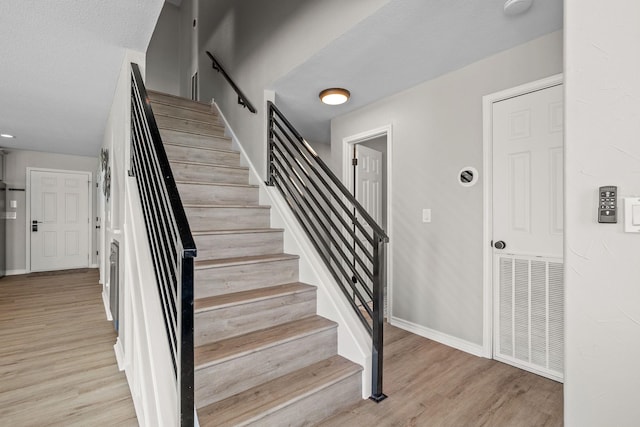 staircase with hardwood / wood-style floors and a textured ceiling