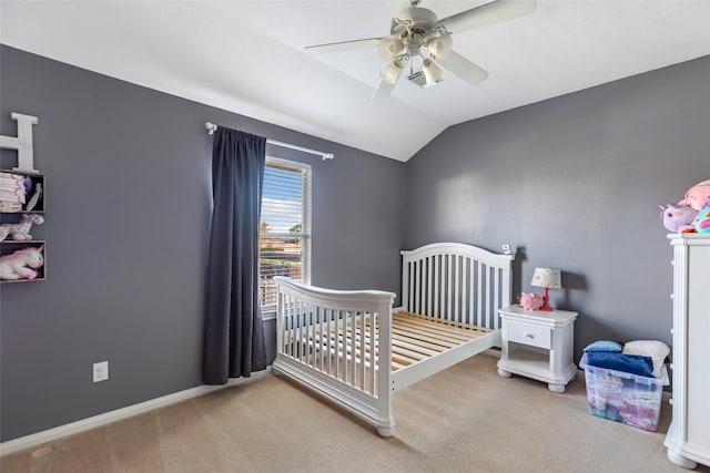 bedroom with ceiling fan, vaulted ceiling, light colored carpet, and a nursery area