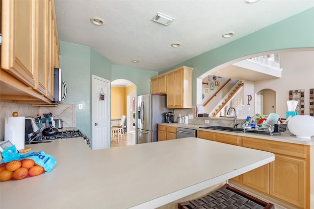 kitchen with kitchen peninsula, appliances with stainless steel finishes, tasteful backsplash, and sink