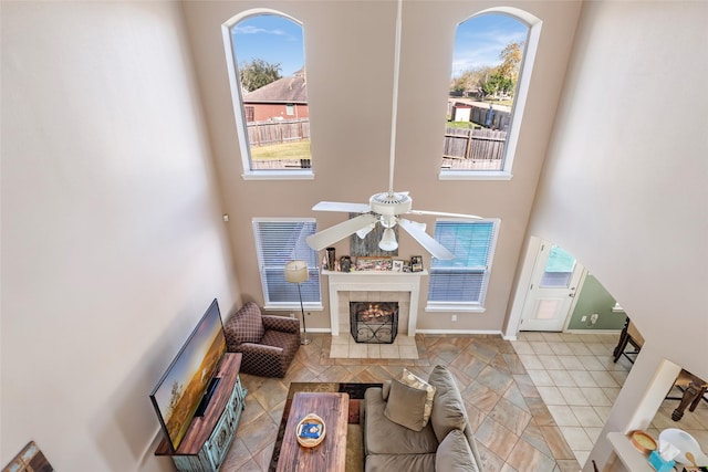 tiled living room featuring plenty of natural light, a towering ceiling, and a fireplace