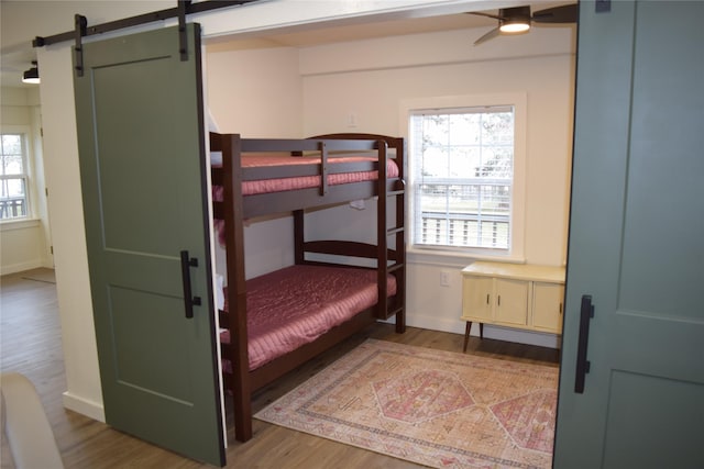 bedroom featuring a barn door, hardwood / wood-style flooring, and ceiling fan