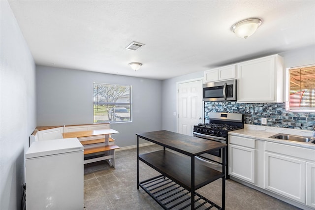 kitchen with appliances with stainless steel finishes, tasteful backsplash, white cabinetry, and sink