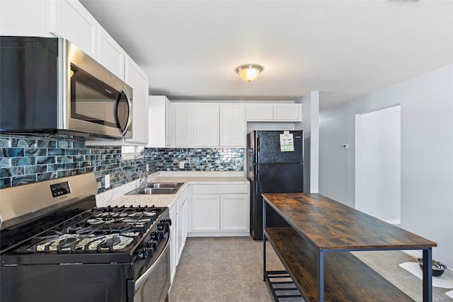 kitchen featuring white cabinetry, sink, backsplash, light tile patterned flooring, and appliances with stainless steel finishes